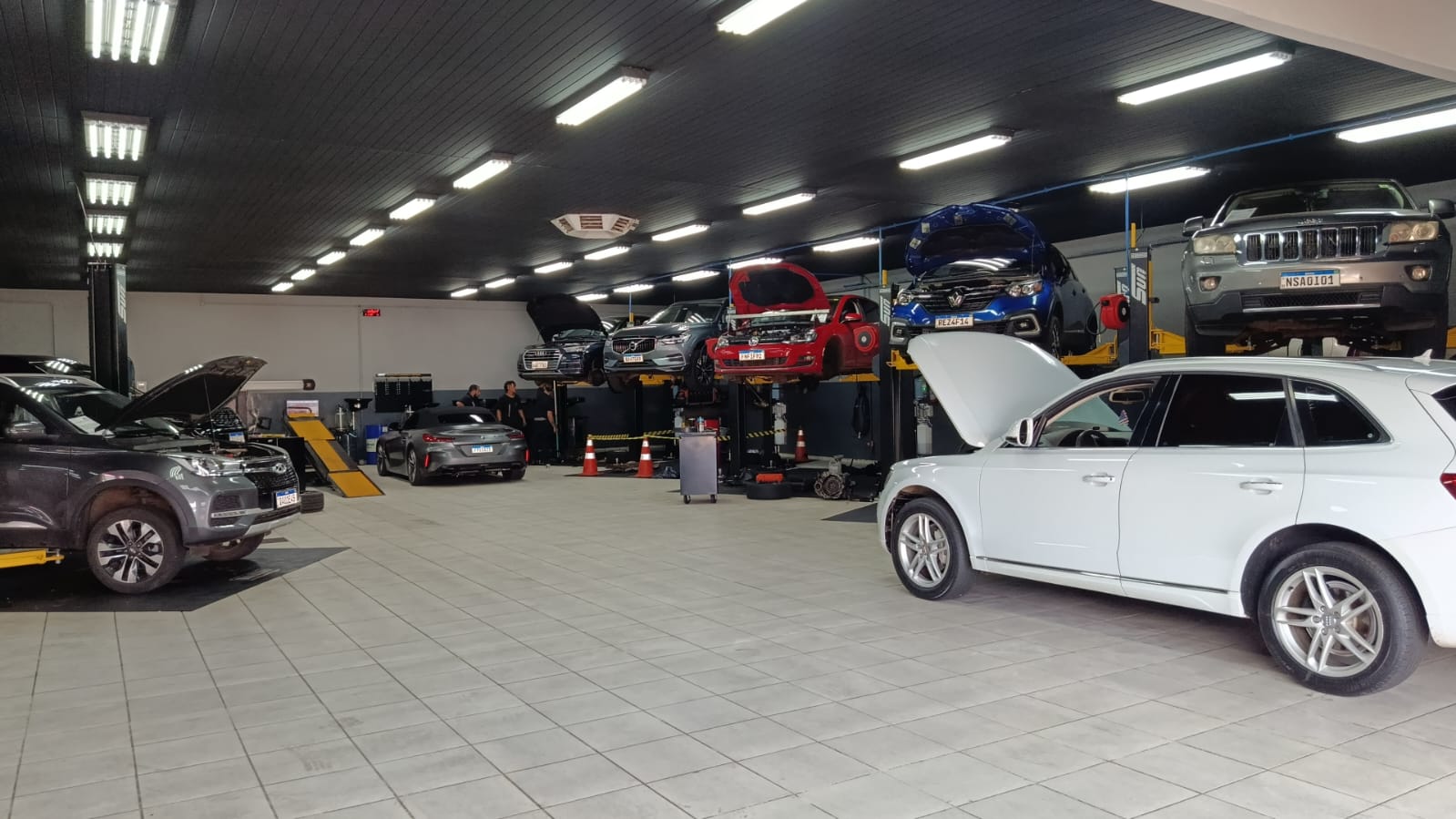 Interior da Oficina Premium Service em Campo Grande com carros importados em elevadores